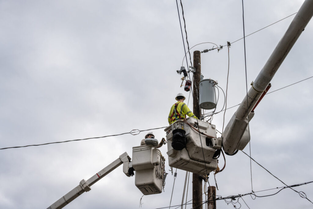 Line workers in bucket trucks working on an overhead distribution pole
