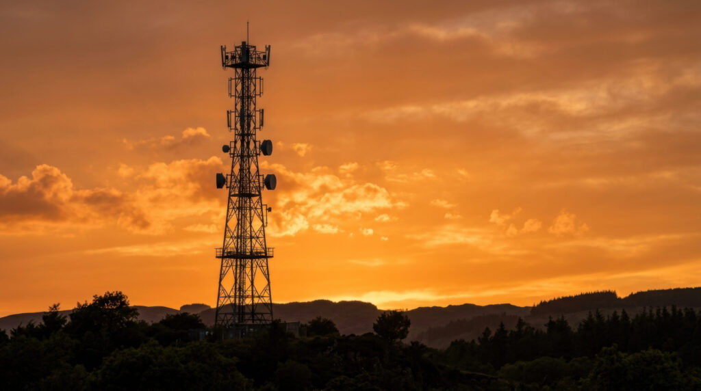 Telecommunications tower silhouetted against an orange sunset