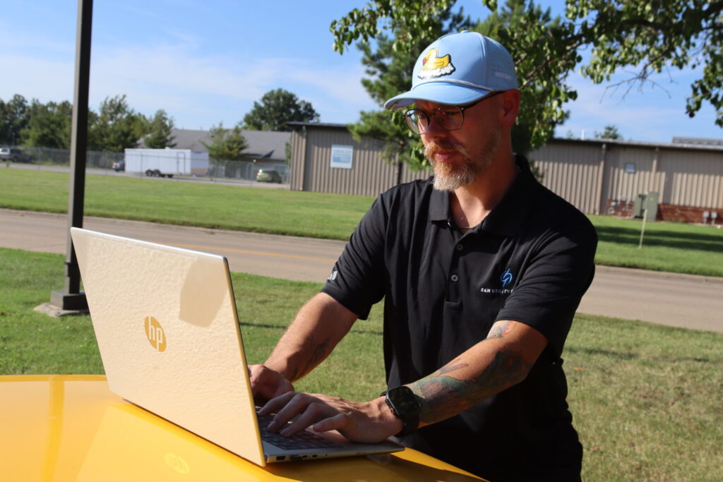 S&M team member working on a laptop outdoors at a project site