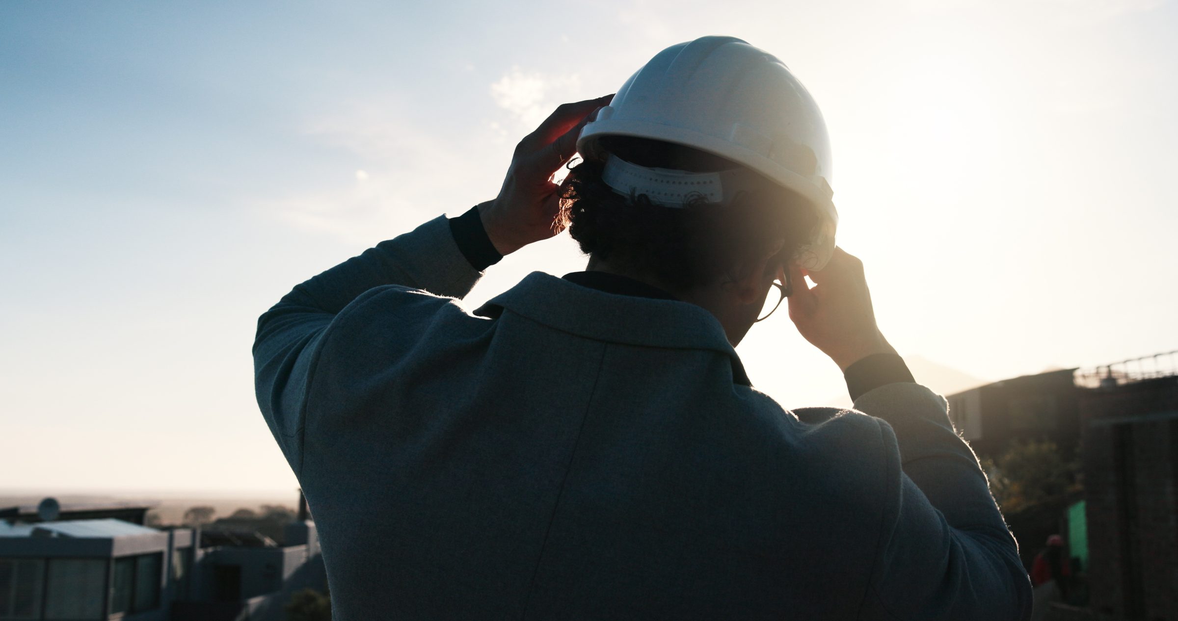 Engineer adjusting a white hard hat in bright sunlight