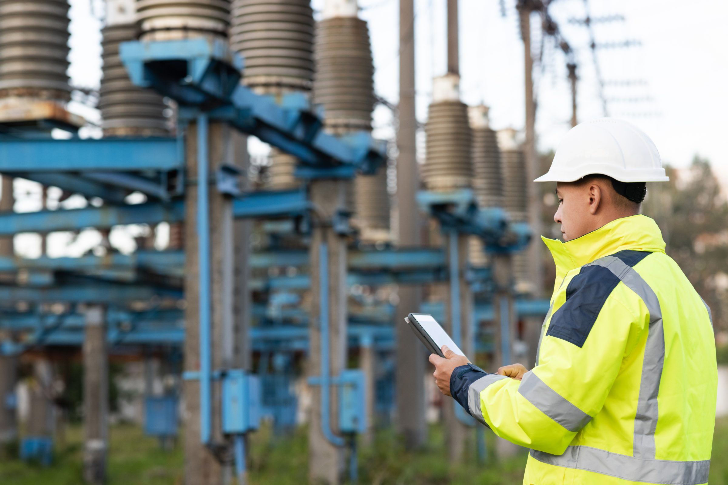 Engineer with a tablet inspecting substation equipment