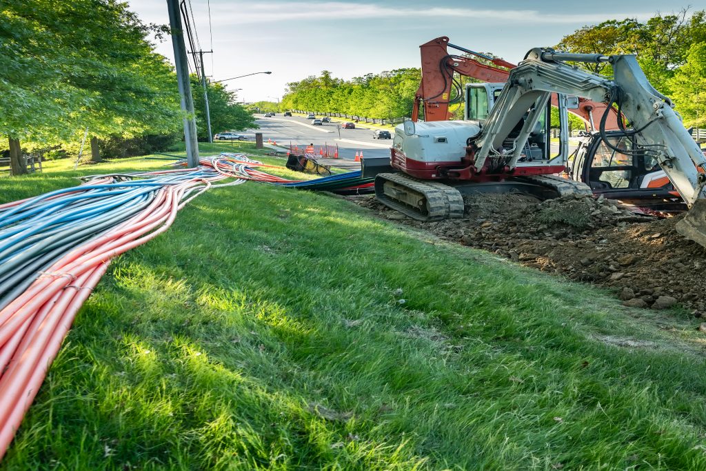 Fiber conduit laid along a roadside next to an excavator