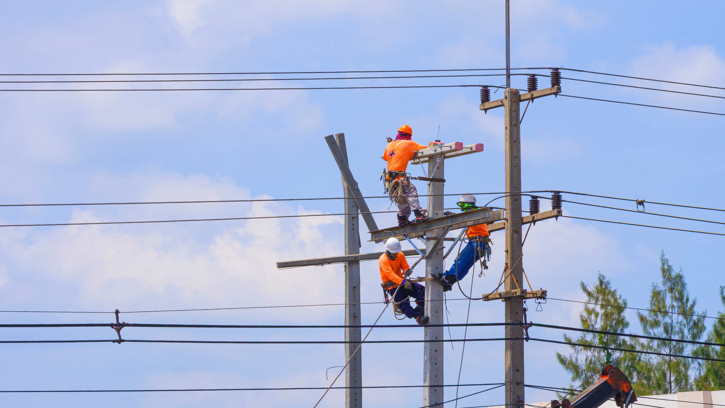 Two lineworkers working on utility poles