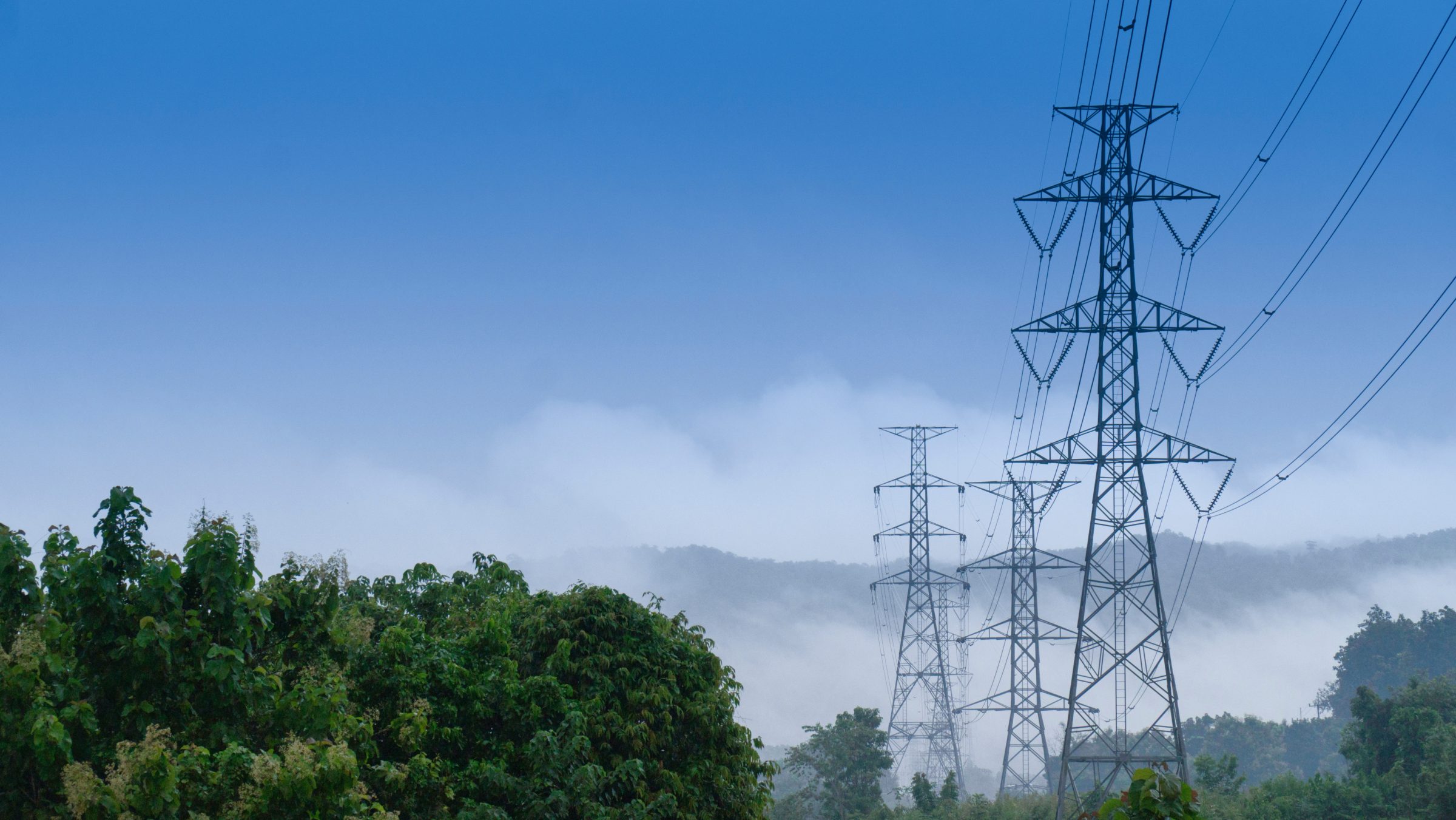 Transmission towers rising above misty hills
